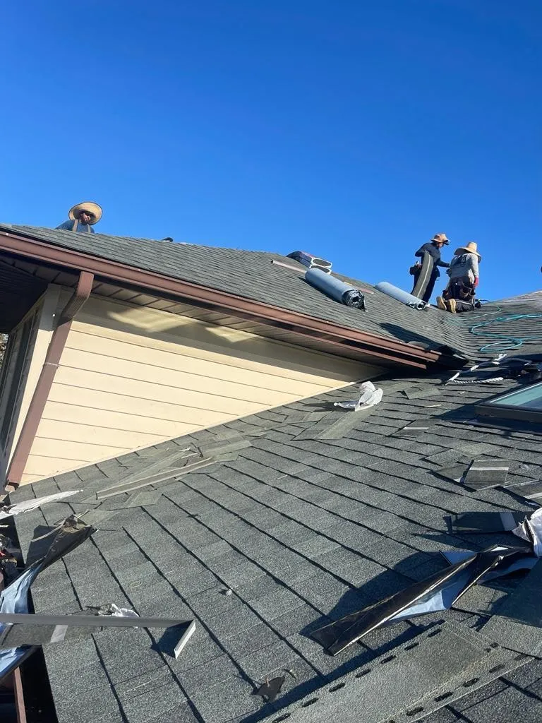 Crew working the ridge line of a new roof under a clear sky