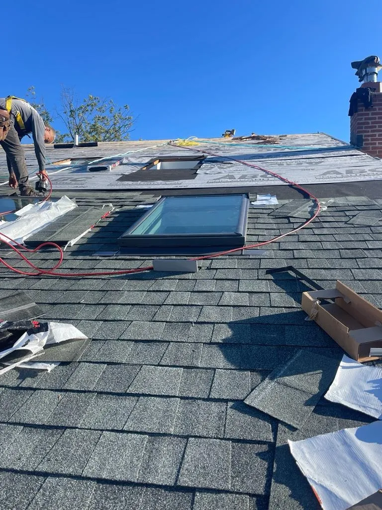 Roofers flashing a skylight on a new shingle roof